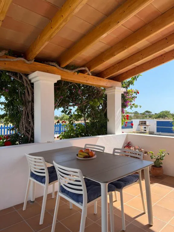 Terraza cubierta con mesa y sillas junto a un jardín de buganvillas, Can Vicent Sita