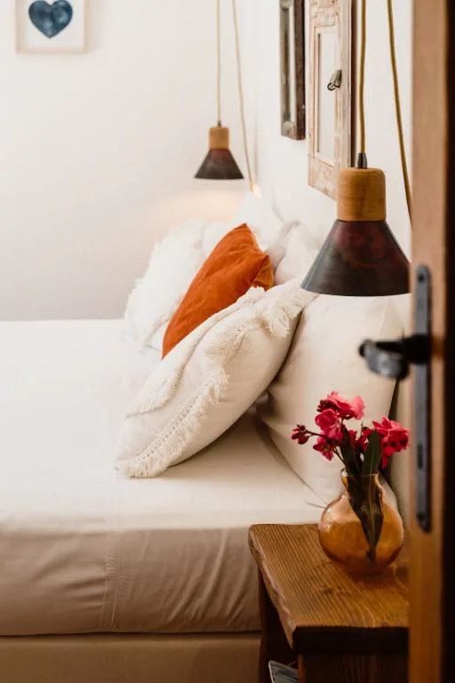 Cabecero con lámparas colgantes de cuero y flores junto a la cama, Can Vistabella