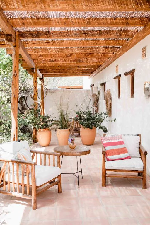 Pérgola de cañizo con sillones de fibra natural y macetas de barro, Can Vistabella
