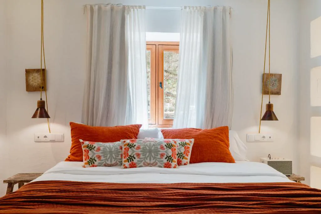 Dormitorio de estilo boho-chic con cojines en terracota, Can Vistabella Boutique Resort, en Sant Antoni de Portmany, Ibiza