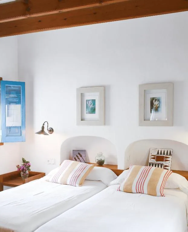 Dormitorio con ventana azul tradicional y ropa de cama a rayas, Can Xicu Castello