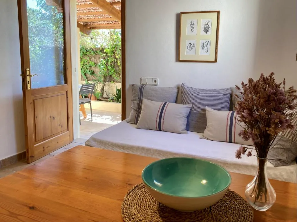 Salón con sofá cama y puerta de madera abierta al porche, Can Xicu Castello