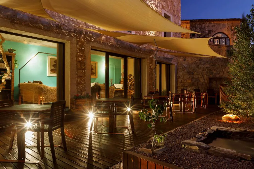 Terraza de madera iluminada de noche con toldos en Capítulo Trece, Maderuelo
