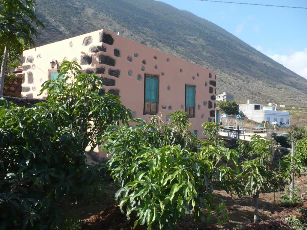 Fachada tradicional herreña en tonos coral con contraventanas verdes, Casa de Mi Abuela Maria, en Los Llanillos, La Frontera, El Hierro