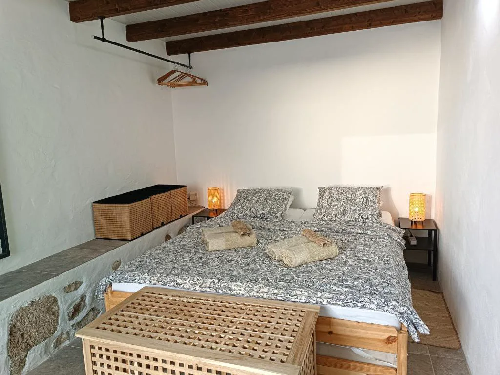 Dormitorio con techo de vigas de madera vista y baúl de mimbre a los pies de la cama, Casa Bailarina