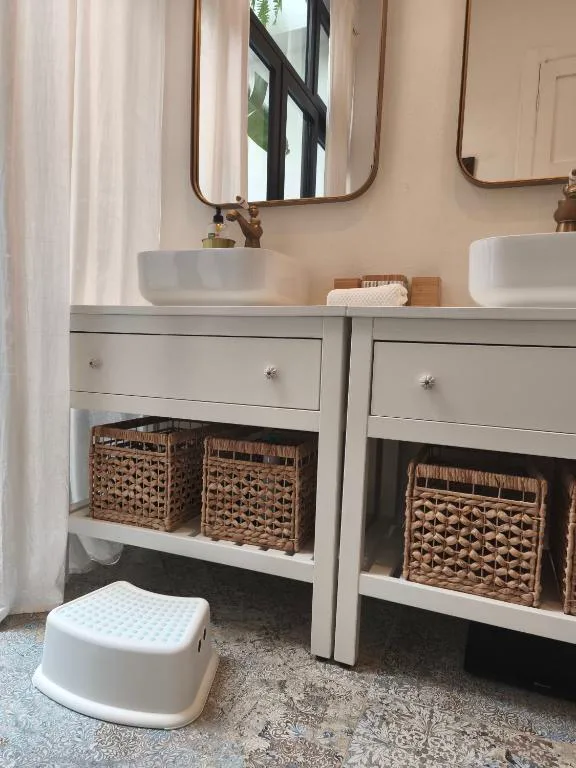 Doble lavabo de diseño con espejos dorados y cestas de mimbre bajo la encimera, Casa Bailarina