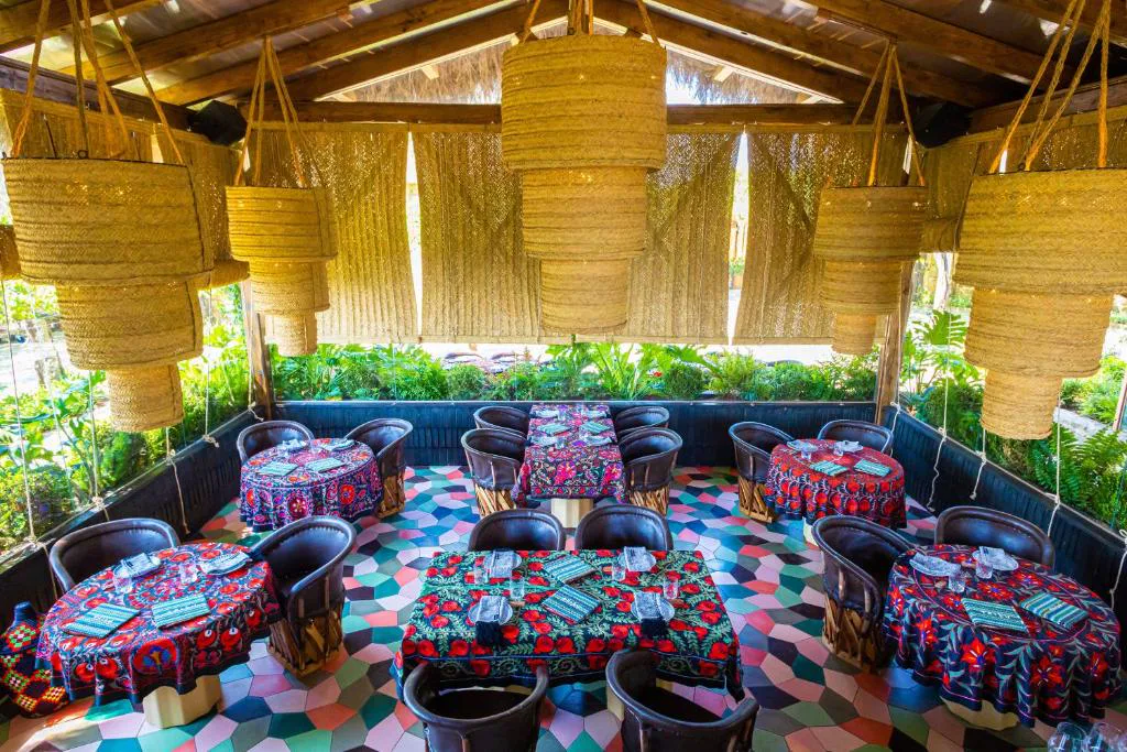 Restaurante Tribu con mesas bajo techo de fibra natural y ambiente selvático, Casa Beatnik