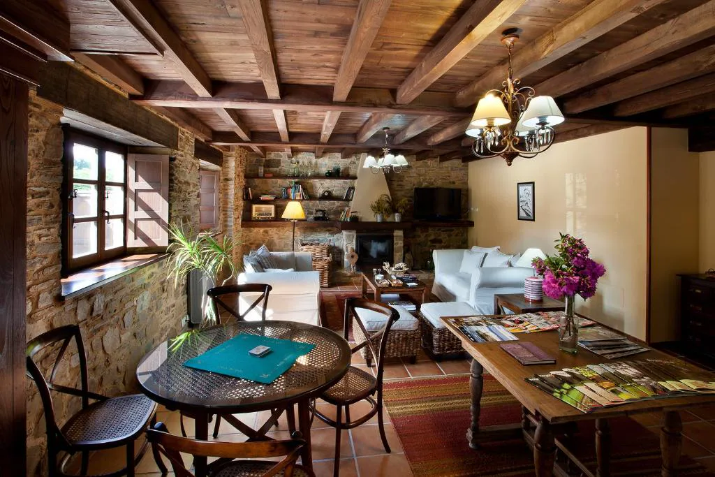 Salón con chimenea de piedra y trofeos antiguos en el Hotel Casa Cachón