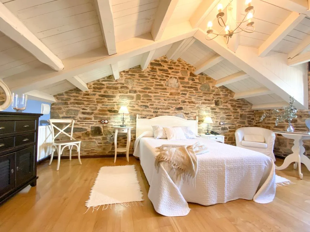 Dormitorio bajo cubierta con pared de piedra vista en el Hotel Casa Cachón