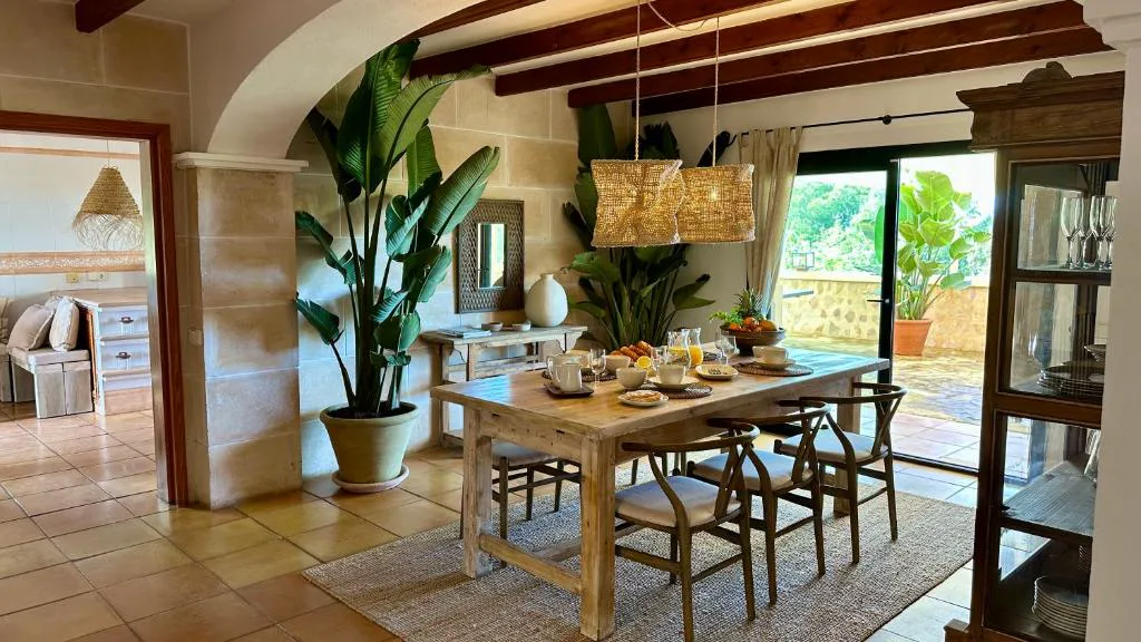 Comedor con plantas tropicales y vigas de madera vista, Casa en Cala Vadella