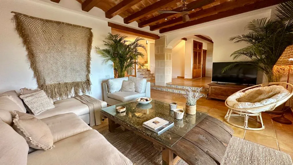 Salón con sofás claros y arco de piedra tradicional ibicenco, Casa en Cala Vadella