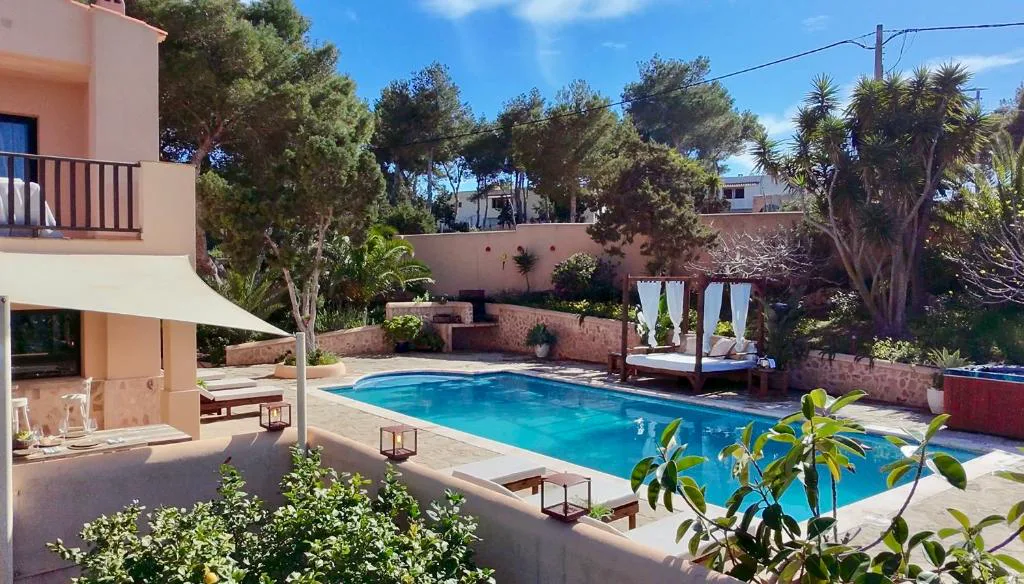 Piscina exterior con camas balinesas y jardín mediterráneo, Casa en Cala Vadella