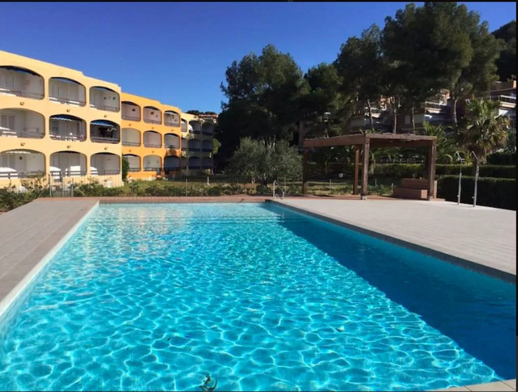 Piscina rectangular junto a un edificio de apartamentos amarillo