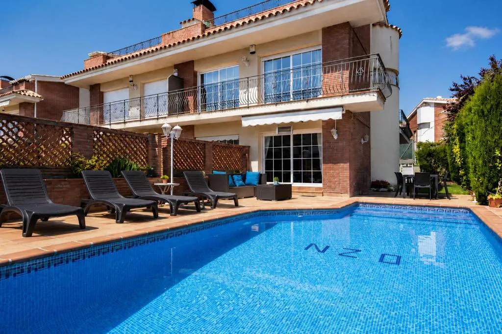Piscina con la casa de tres alturas al fondo