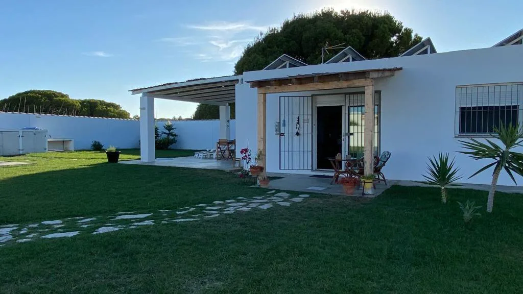 Casa blanca de una planta con porche y césped