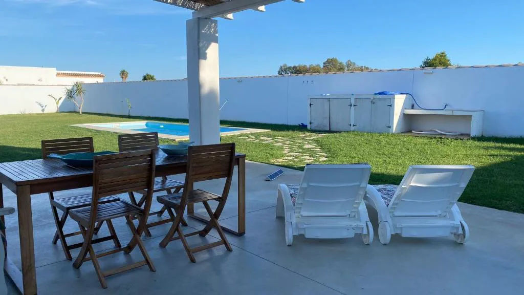 Terraza con mesa y tumbonas junto al jardín