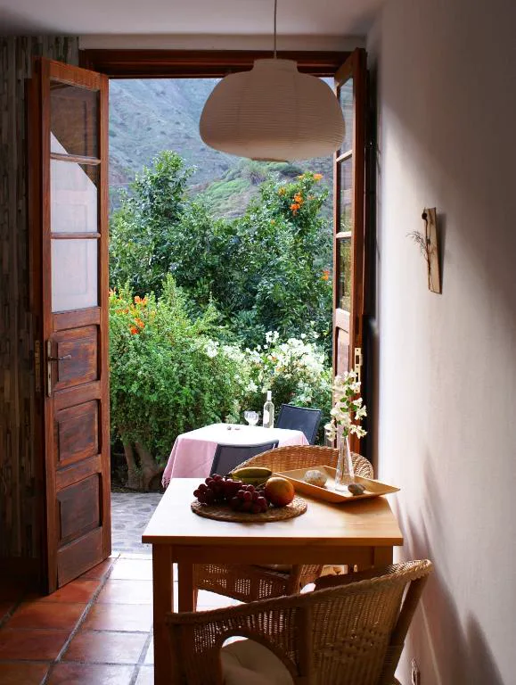 Puertas abiertas al jardín con mesa de desayuno y flores de buganvilla, Casa Creativa