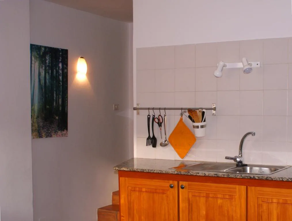 Cocina equipada con encimera de granito y utensilios colgados, Casa Creativa