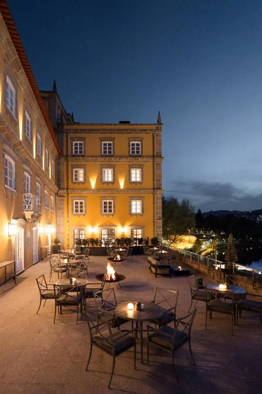 Terraza exterior iluminada con brasero y vistas nocturnas al valle, Casa da Calçada