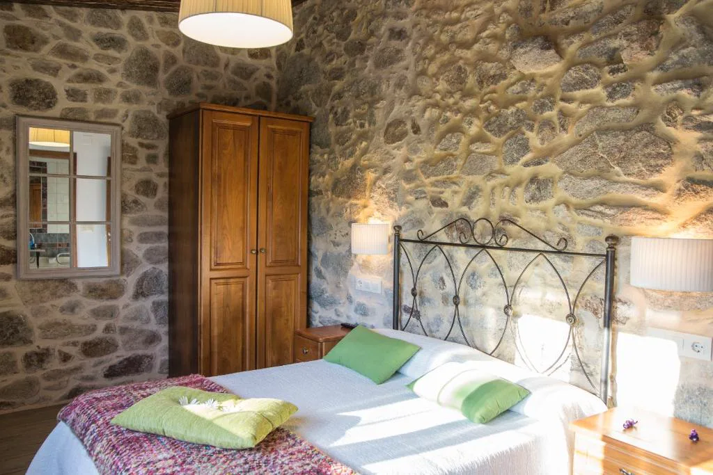 Dormitorio de piedra vista con cabecero de forja y armario de madera maciza, Casa das Fiadeiras de Nemiña