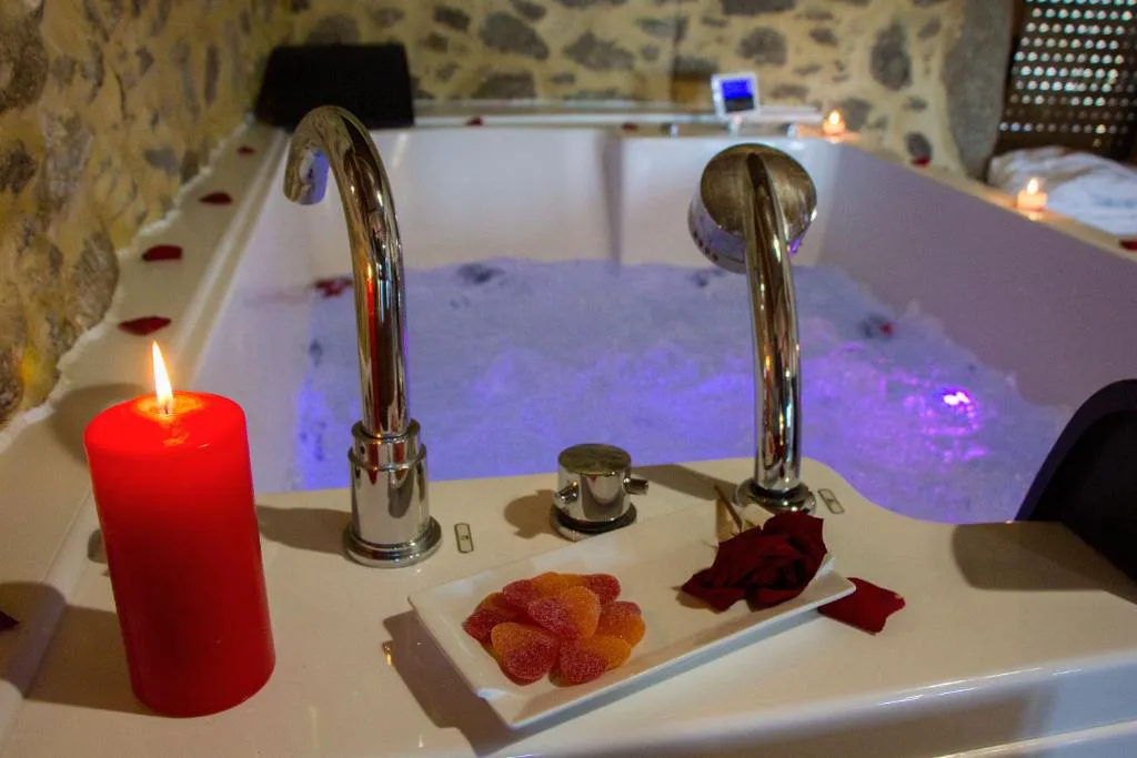 Detalle del jacuzzi con vela roja, gominolas y rosa sobre la bañera, Casa das Fiadeiras de Nemiña