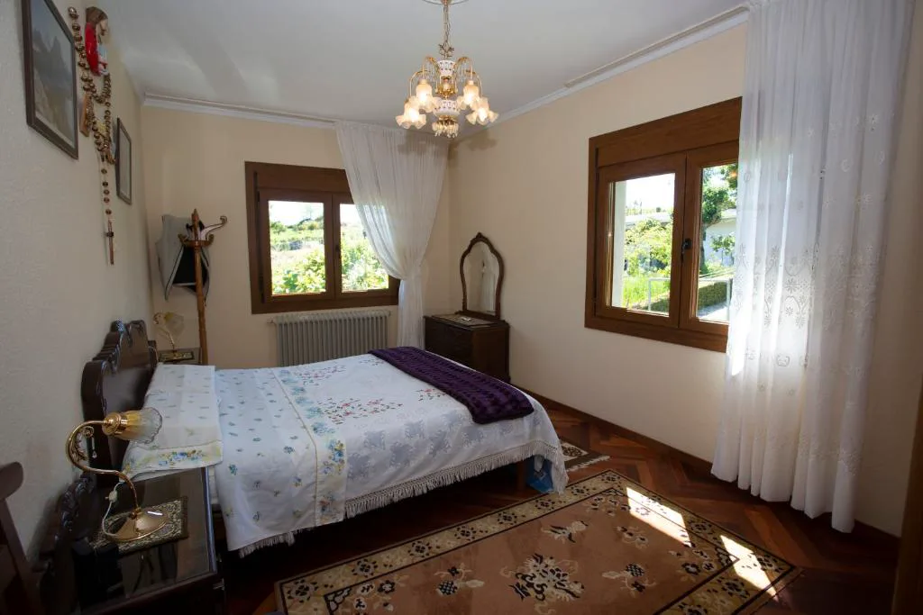 Segundo dormitorio de estilo clásico con cómoda de madera y ventanas al jardín