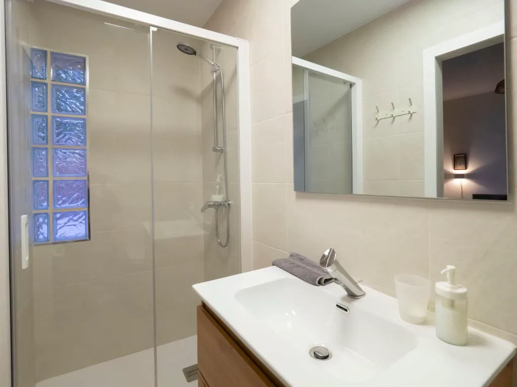 Baño con ducha de cristal y lavabo blanco
