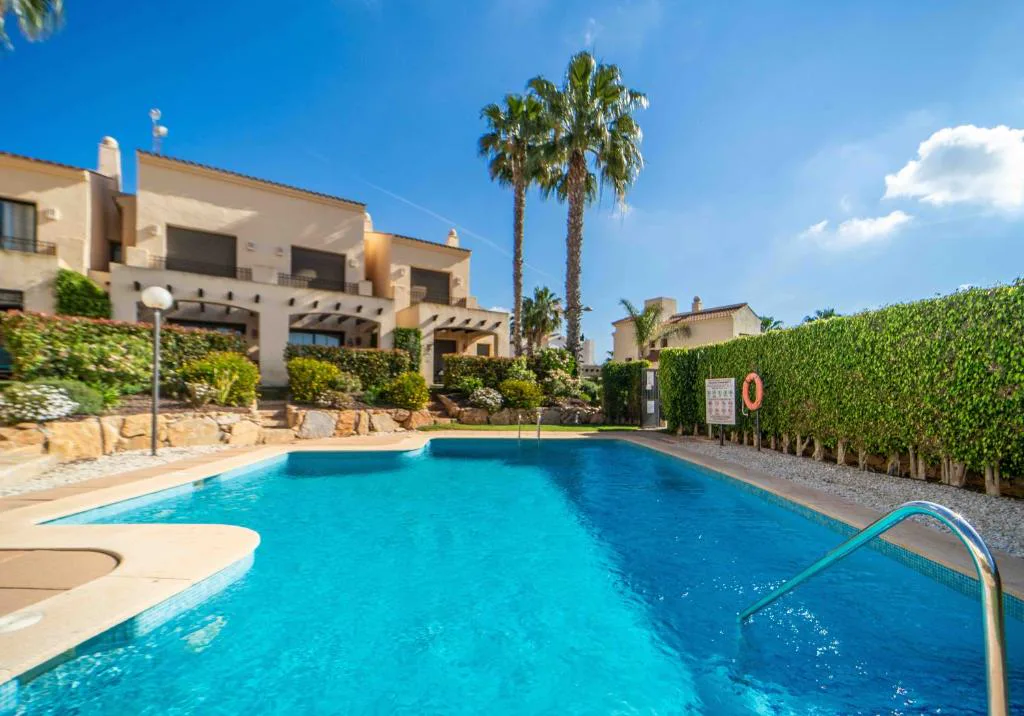 Piscina comunitaria con palmeras junto a las casas de piedra
