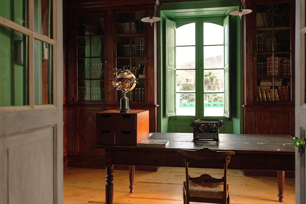 Biblioteca de madera con máquina de escribir antigua y ventana verde, Hotel Emblemático La Casa de los Naranjos