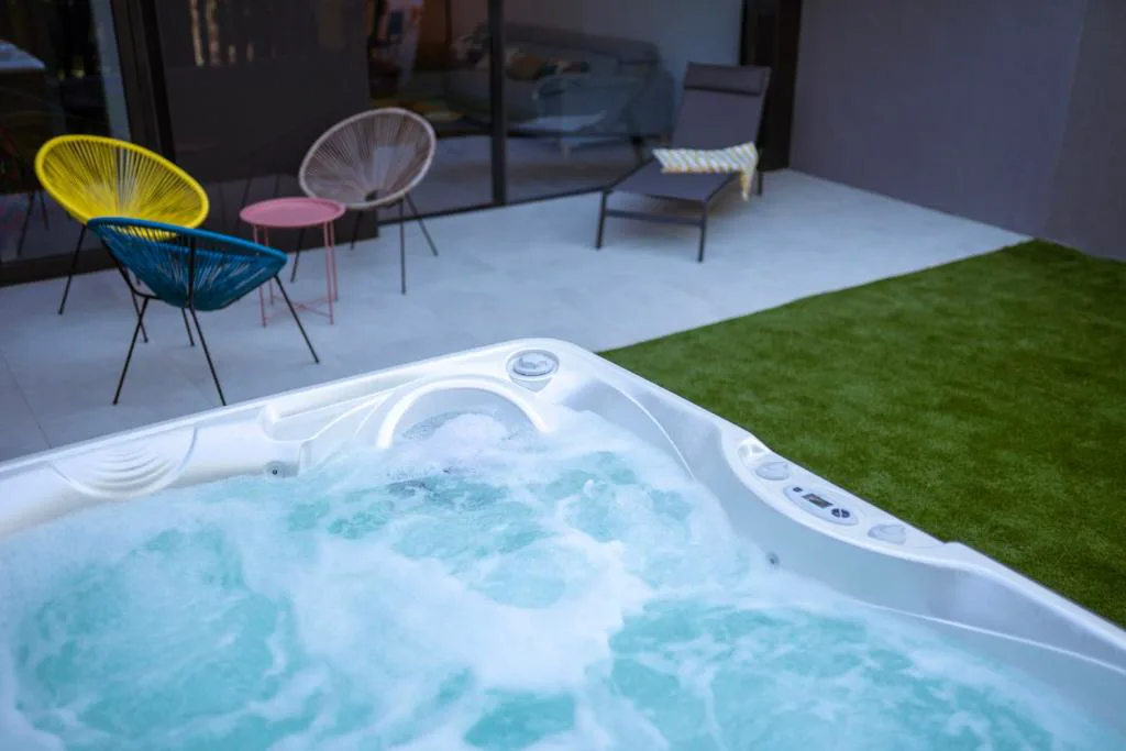 Jacuzzi burbujeante en un patio con césped y sillas de colores