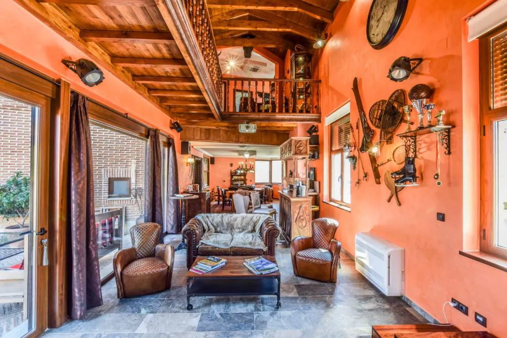 Salón con techo de vigas, sillones de cuero y objetos de viaje
