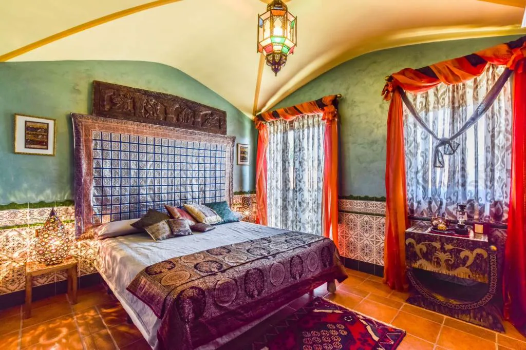 Dormitorio con cabecero azul, colgaduras rojas y lámpara