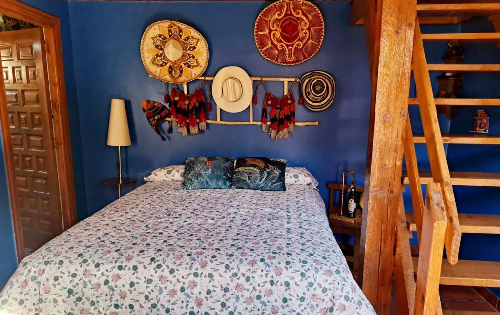 Dormitorio con cama de flores, escalera y platos decorativos