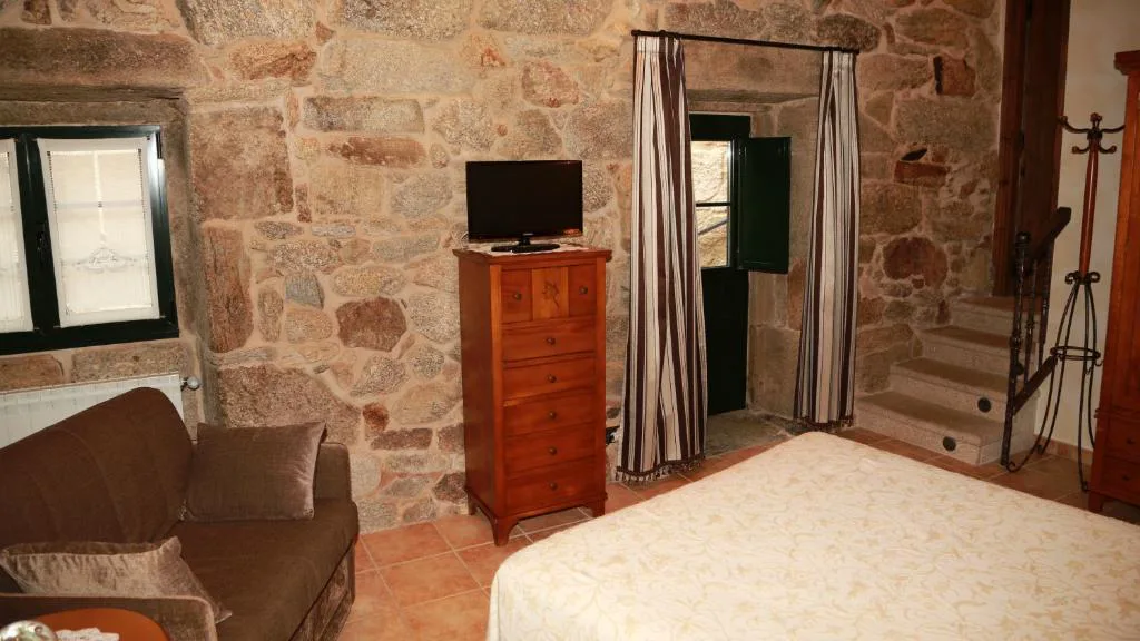Dormitorio de piedra vista con sofá y escalera de madera, Casa do Sear