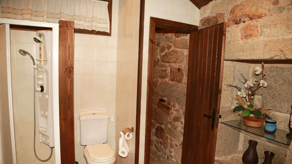 Baño rústico de piedra con ducha hidromasaje y puerta de madera maciza, Casa do Sear