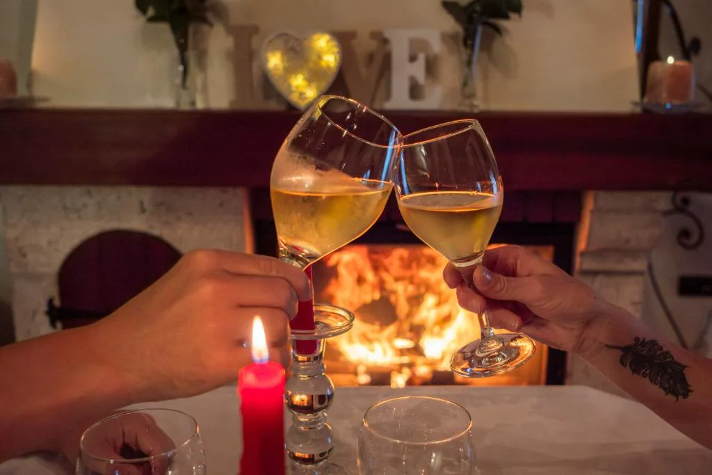 Brindis con copas de cava junto a la chimenea encendida, decoración con la palabra LOVE, Casa do Sear