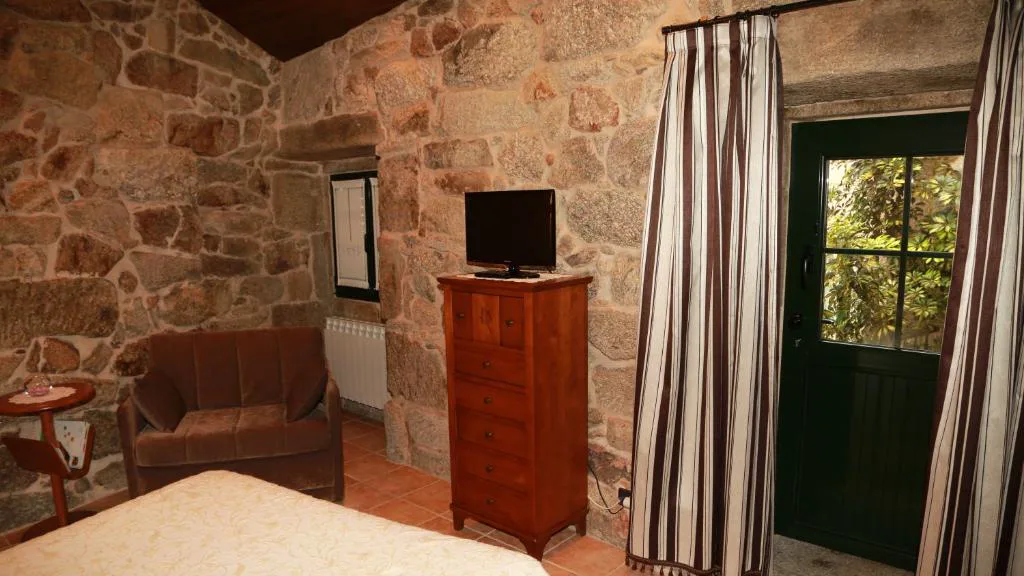 Dormitorio de piedra vista con sillón de terciopelo marrón, Casa do Sear