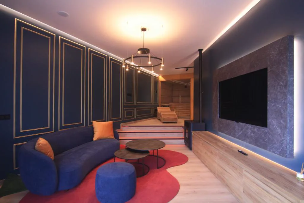 Salón con sofá azul y cojines mostaza junto a la sauna, Casa dos Americanos