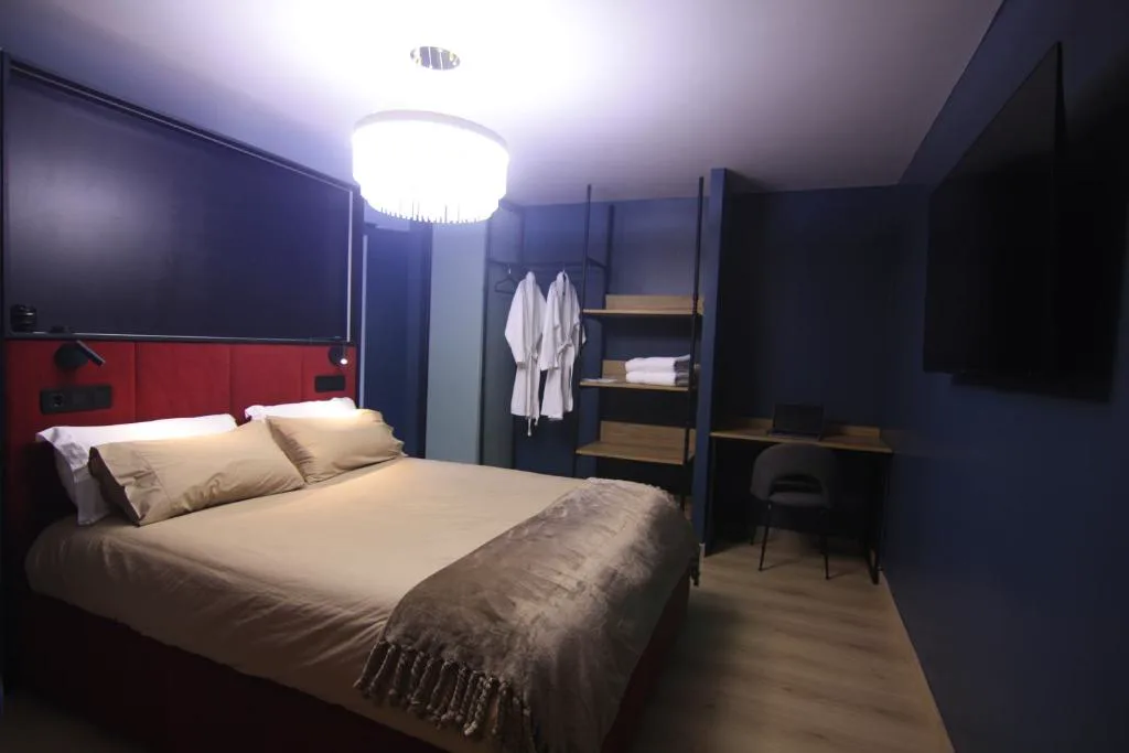 Dormitorio en tonos azul marino con cabecero granate y albornoces colgados, Casa dos Americanos