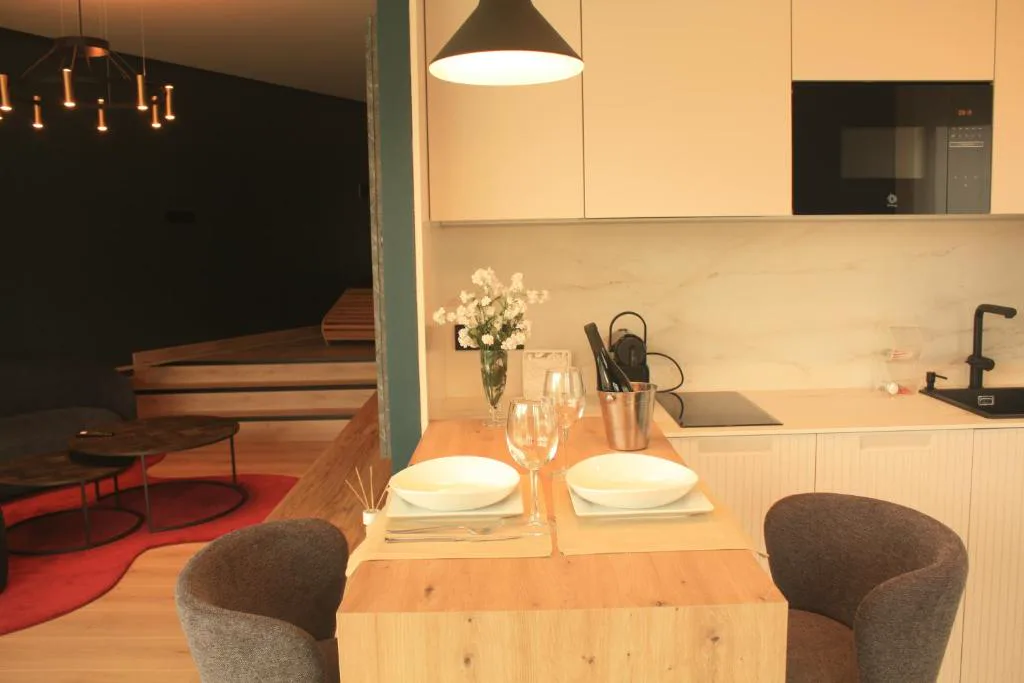 Cocina abierta con mesa vestida para dos junto a flores blancas, Casa dos Americanos