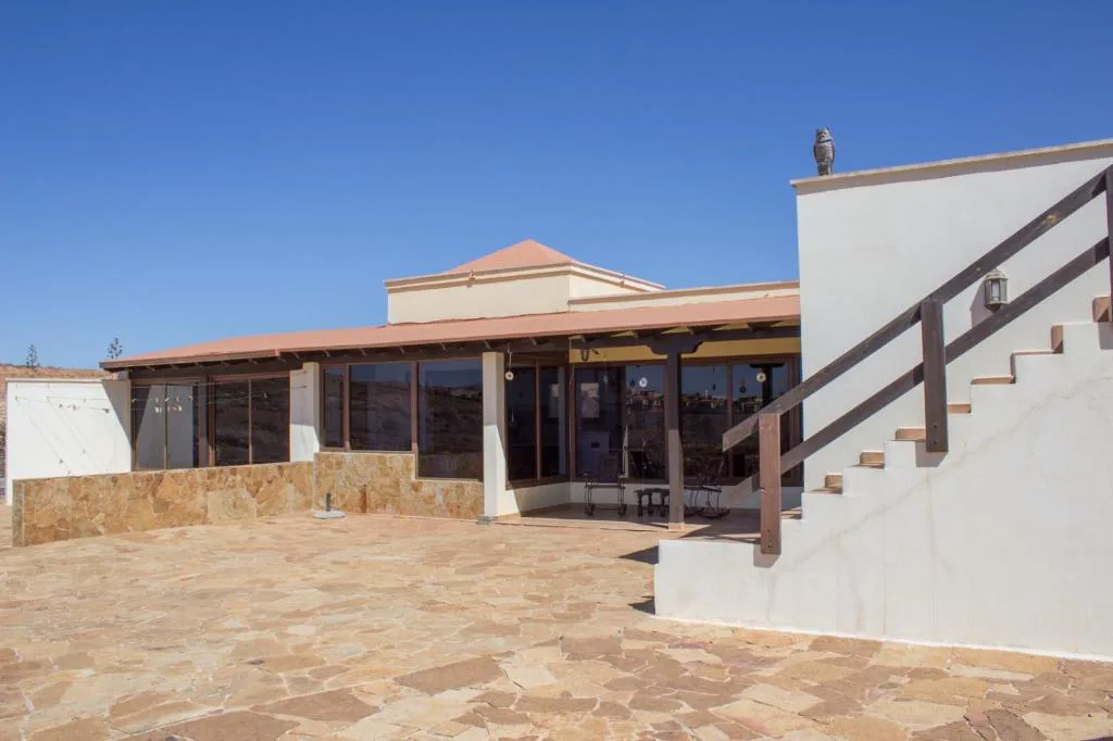 Fachada de la casa con porche acristalado y escalinata de piedra blanca, Casa El Horno