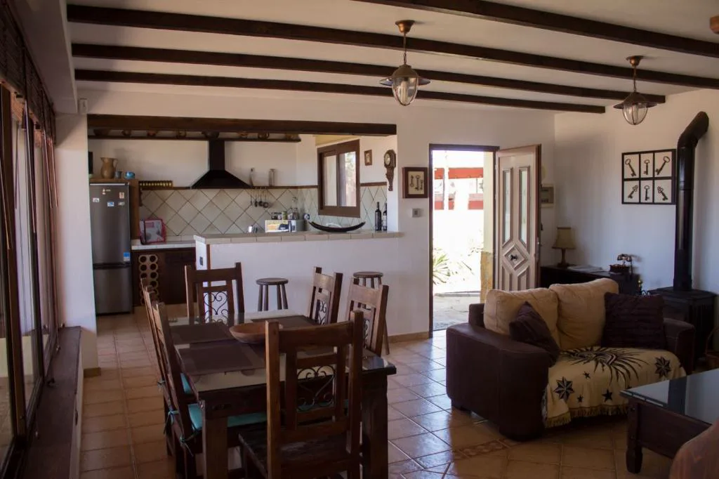 Cocina abierta al salón con techo de vigas de madera oscura, Casa El Horno