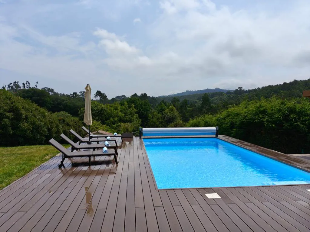Piscina con tarima de madera y tumbonas frente a las colinas