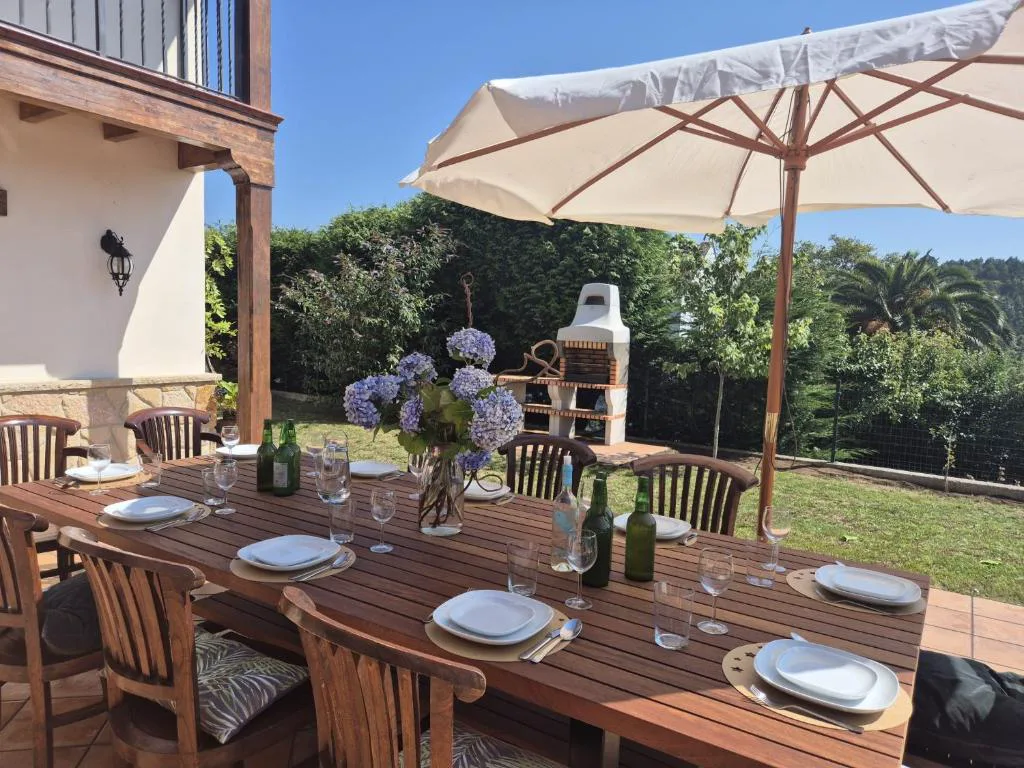 Mesa de comedor exterior con sombrilla y barbacoa