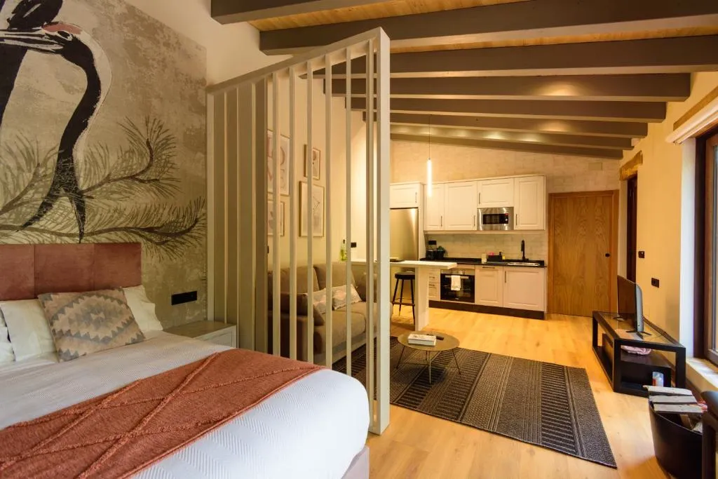 Apartamento con cama, cocina abierta y separador de madera, en Casa Escondida Aveiga