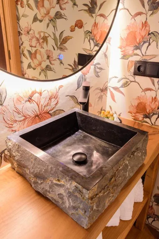 Lavabo de piedra con papel pintado floral en el baño de Casa Escondida Aveiga