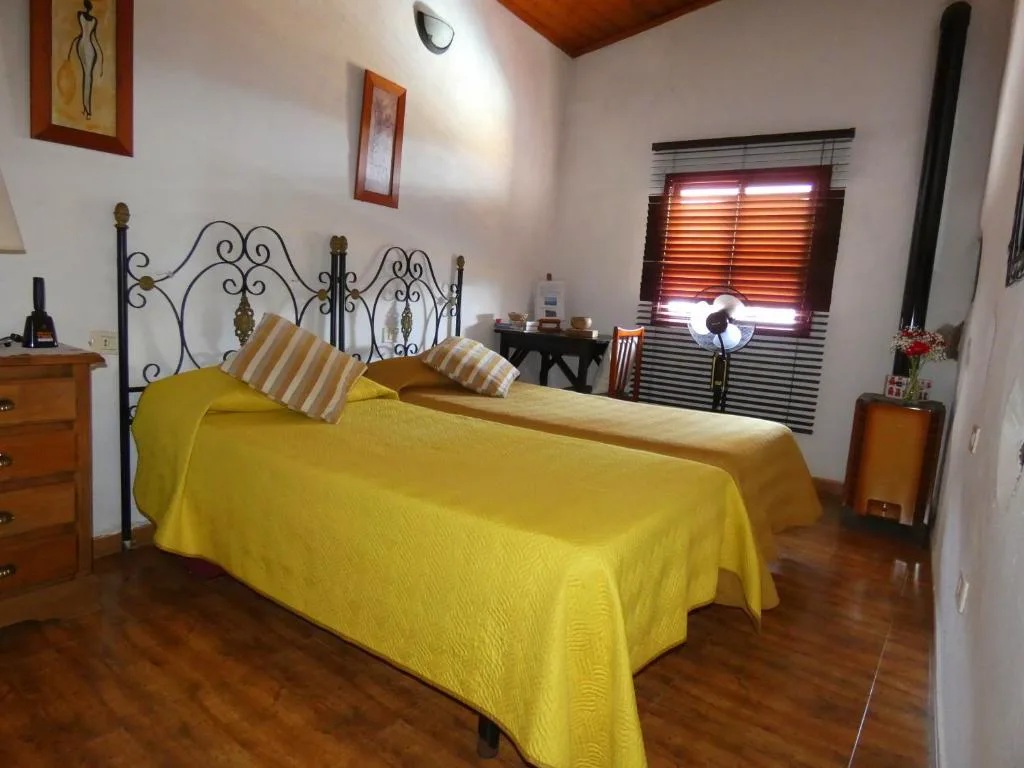 Dormitorio con cabecero de forja negra y colcha amarilla, Casa Goliath