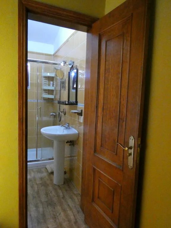 Baño con ducha de obra y puerta de madera maciza, Casa Goliath