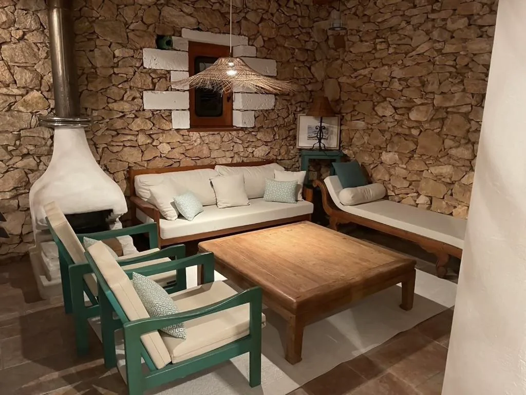 Salón de piedra vista con chimenea y sillones verdes junto a una mesa de centro, Casa Goro