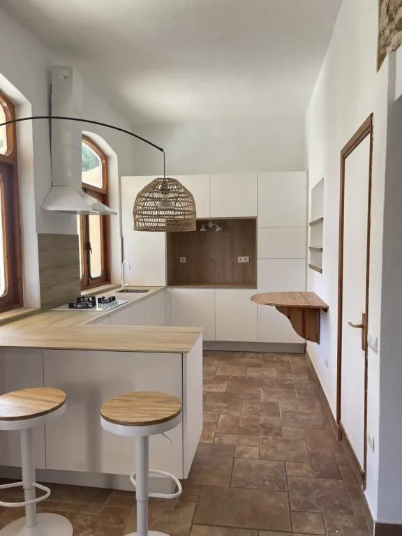 Cocina blanca con lámpara de fibra natural y taburetes de madera, Casa Goro